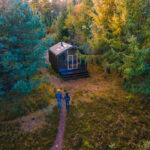 Aerial view of a couple walking towards a modern cabin surrounded by vibrant autumn trees, highlighting the serene beauty of Michigan's natural landscape, ideal for showcasing Michigan web design services focused on outdoor and lifestyle themes.