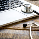 Close-up of a laptop keyboard with a stethoscope, symbolizing the intersection of technology and healthcare, relevant for Michigan web design focused on medical professionals and services.