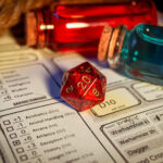 Close-up of a red D20 dice on a character sheet with colorful potion bottles in the background, representing the fun of tabletop gaming. Ideal for Michigan web design focused on gaming or hobbyist websites.