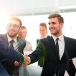 Business professionals shaking hands in a modern office setting, representing collaboration and networking in Michigan web design.